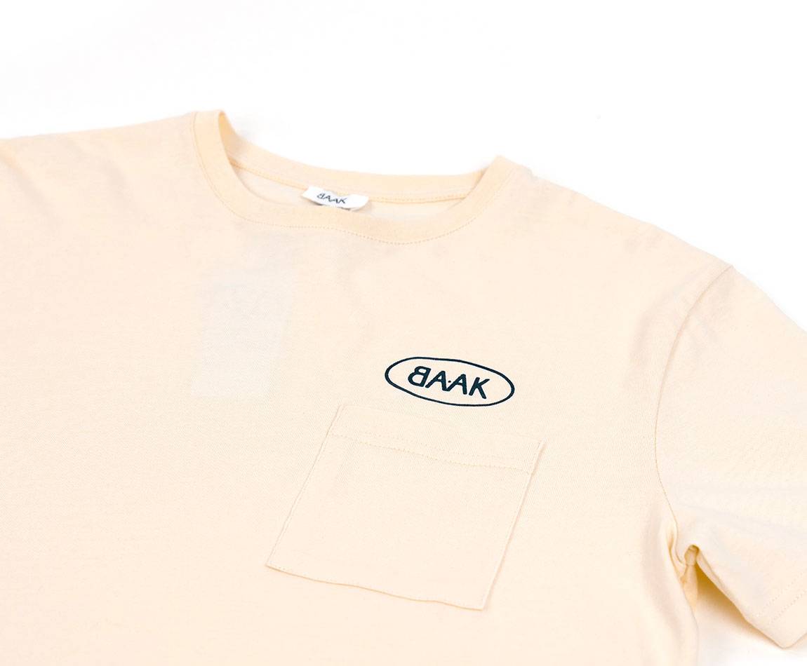 Cream T-Shirt - Short sleeves - Heart pocket on front - Petrol blue BAAK logo silk-screened above pocket Cream T-Shirt - Short sleeves - Heart pocket on front - Petrol blue BAAK logo silk-screened above pocket